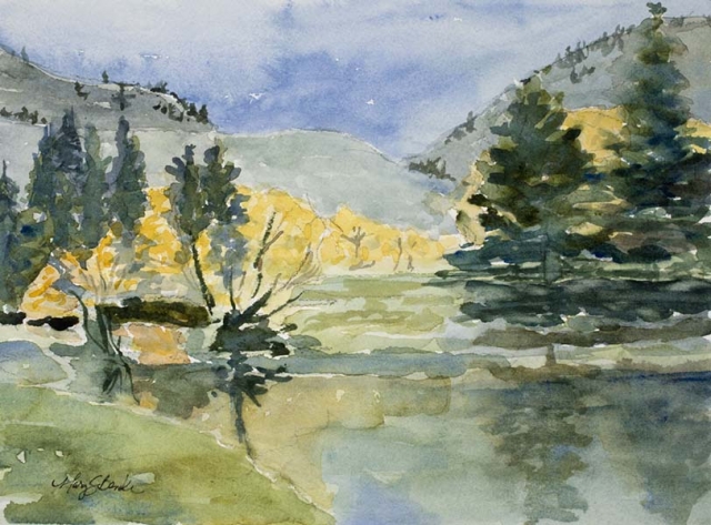 Watercolor landscape painting of yellow trees and pines reflected in a blue lake with foothills in the background by Mary Benke