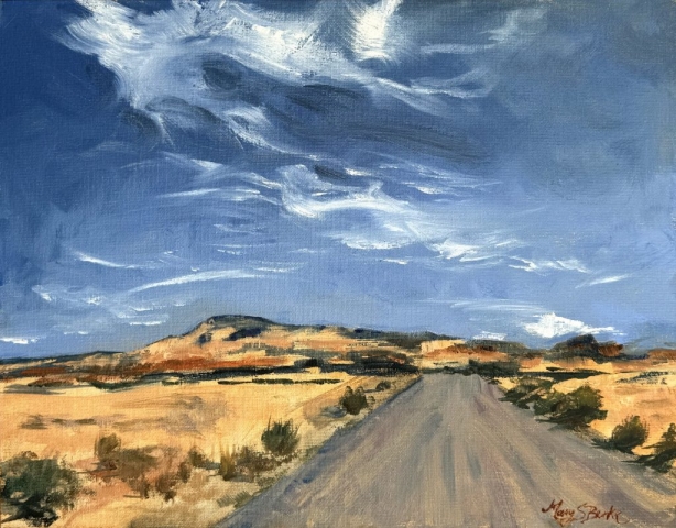 A road stretches into the distance through a desert landscape under a dynamic sky with swirling clouds. Warm tones dominate the scene, highlighting the arid terrain and the expansive sky above by Mary Benke